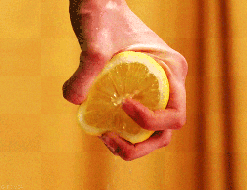 A person's hand squeezing a lemon 