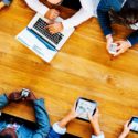 People at a desk using tablets, cell phones, and a laptop - Search Influence