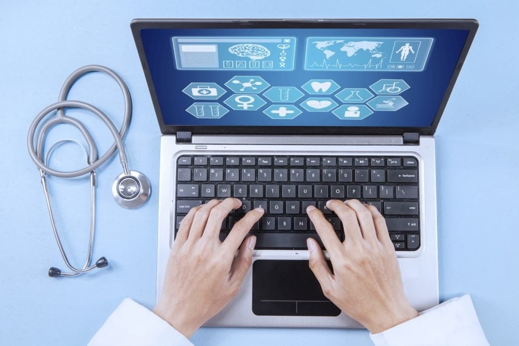 Physician typing on a laptop keyboard