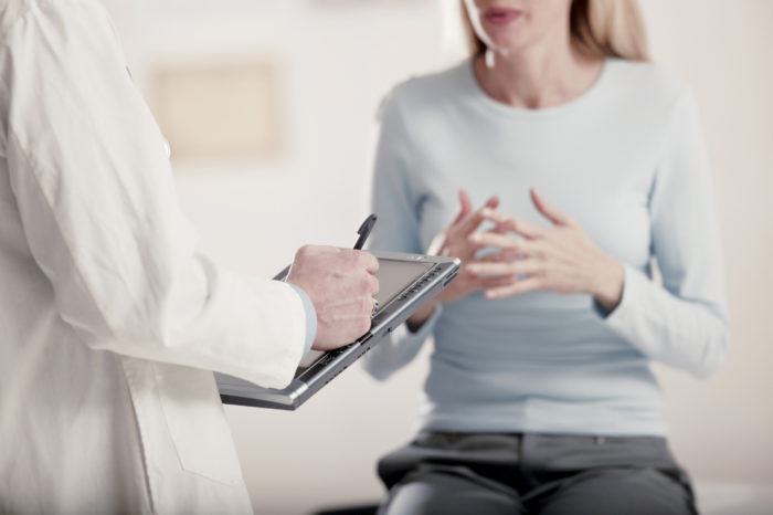 Doctor holding tablet PC talking to patient - Search Influence