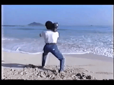 An excited man with a camcorder on a beach - Search Influence