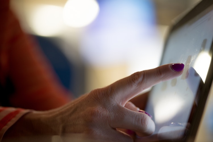 A close-up of a woman touching a screen - Search Influence