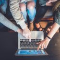 A group of people looking at one laptop screen