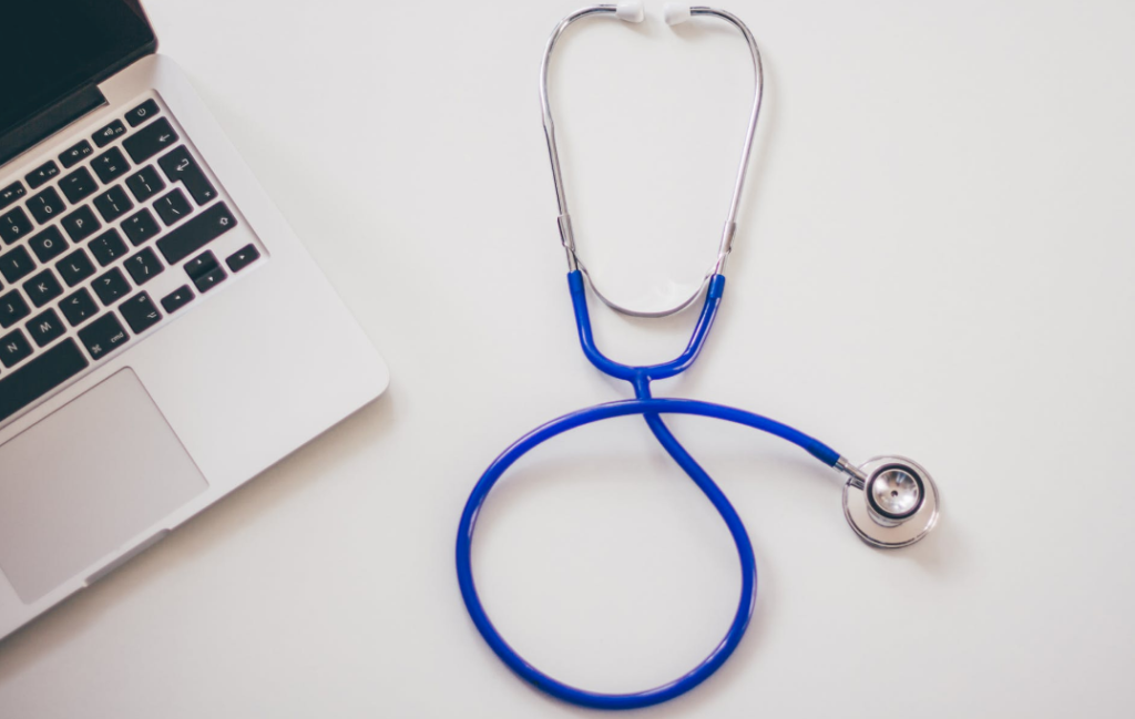 Doctor's stethoscope on desk next to laptop