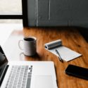 MacBook Pro, white ceramic mug,and black smartphone on table photo