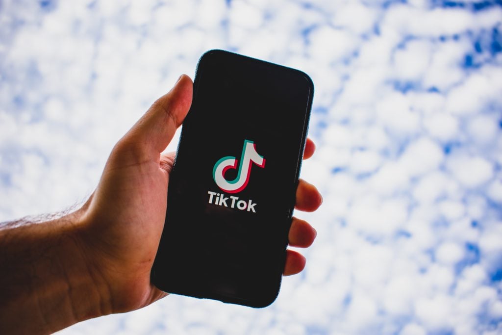 Person holding phone cell phone in the sky with TikTok load screen visible 