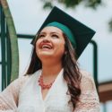 Graduate student smiling wearing a cap and gown at graduation