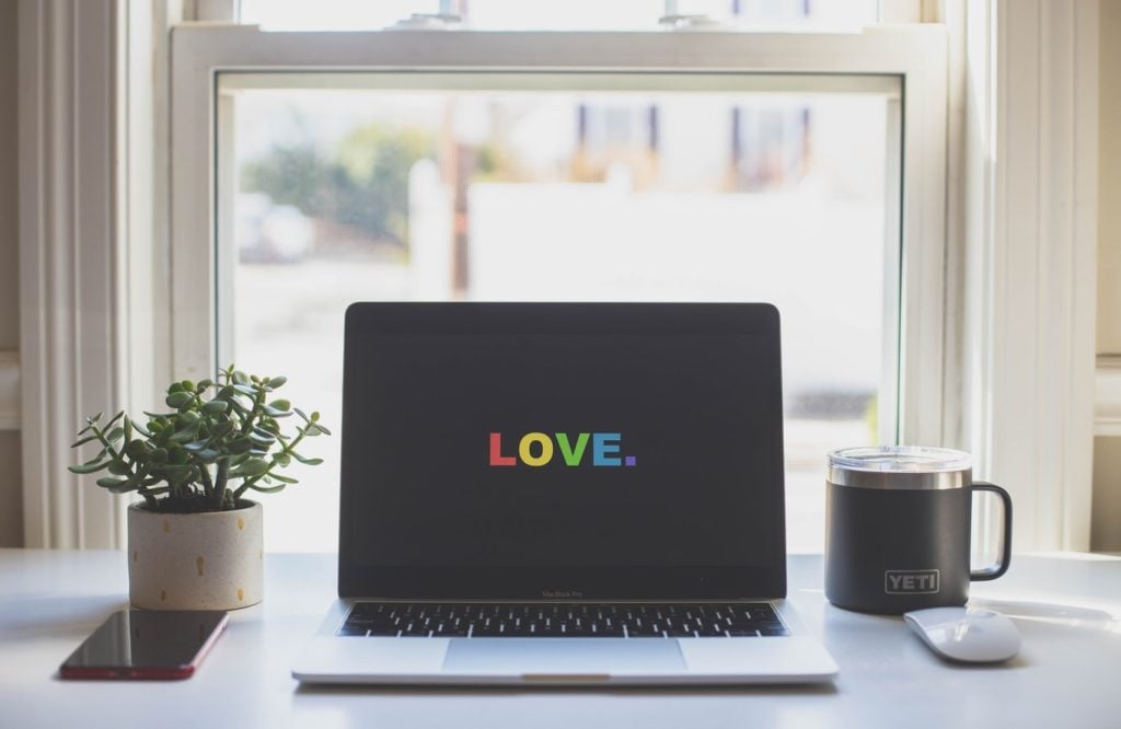 Laptop in front of window on desk with love in rainbow color