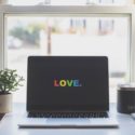 Laptop in front of window on desk with love in rainbow color