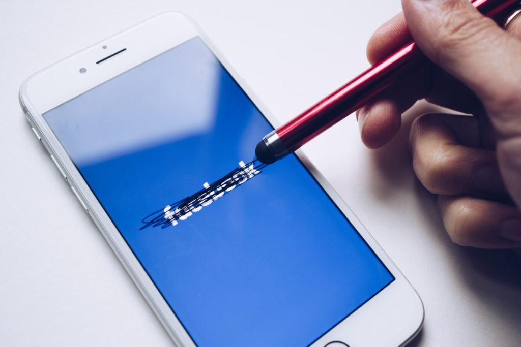 A person scratching out Facebook's name on a smart phone with a stylus 