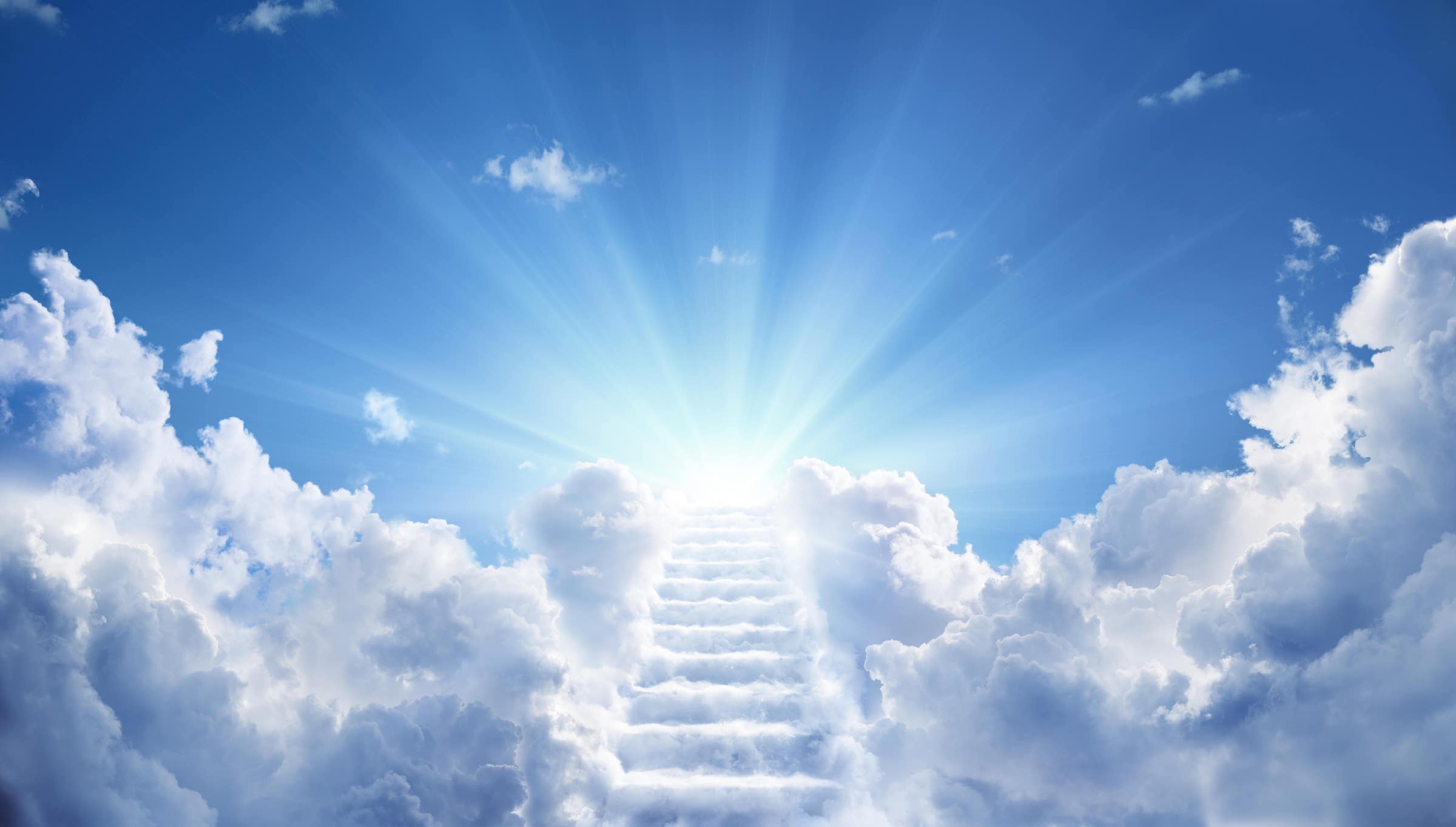 A stairwell covered and surrounded by clouds leading into a blue sky