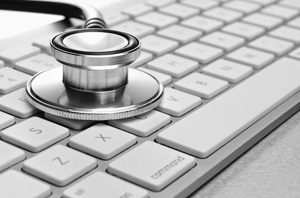 A stethoscope sitting on top of a keyboard representing online healthcare