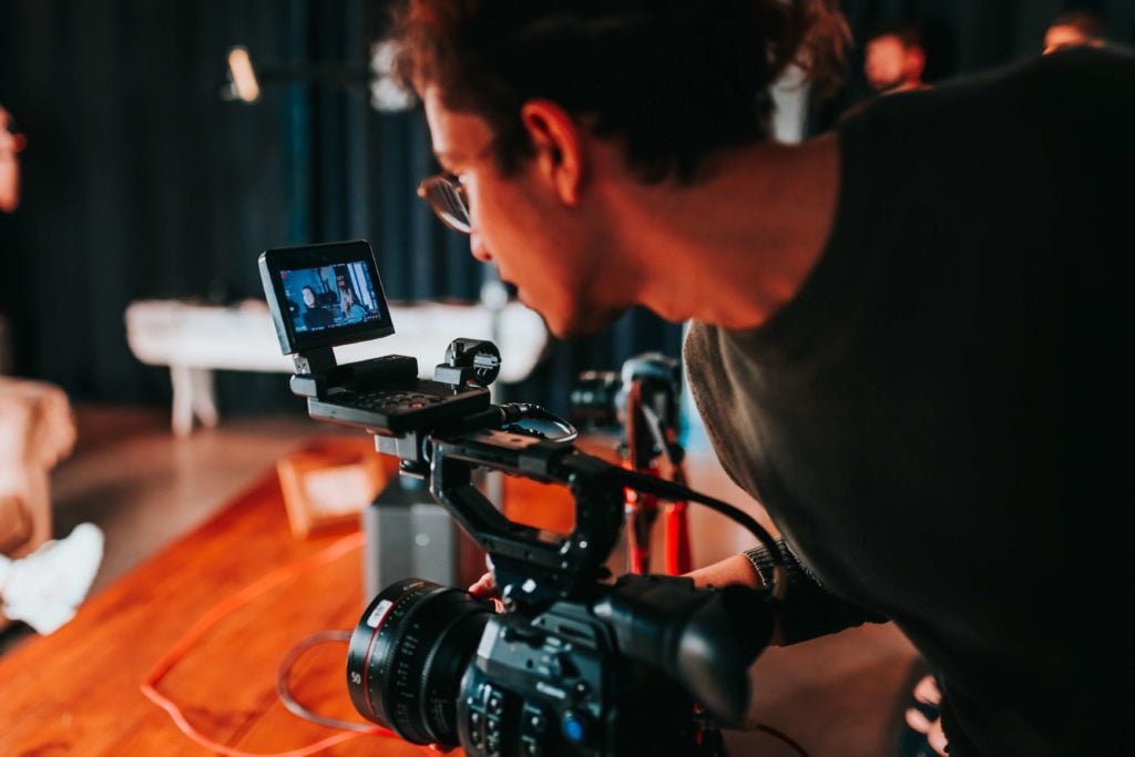 Person behind a video camera gathering assets for a business