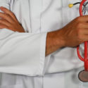 doctor in white coat holding a stethoscope