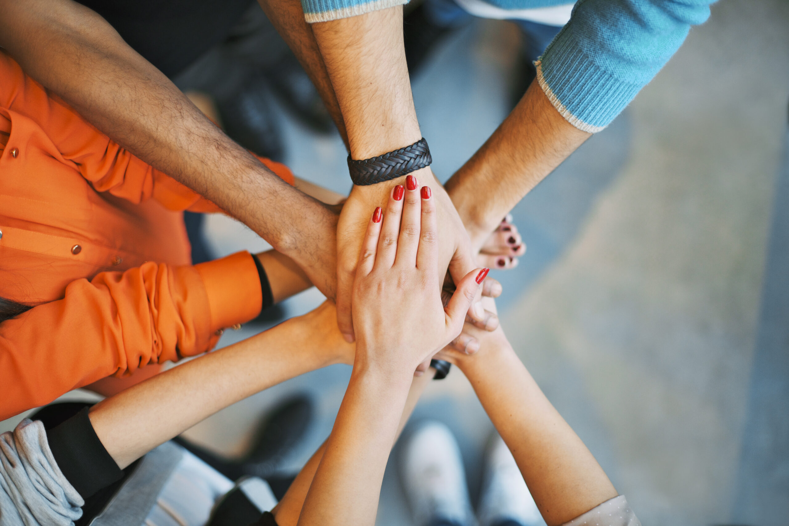 Image of stacked hands showing the teamwork within a higher education marketing agency.
