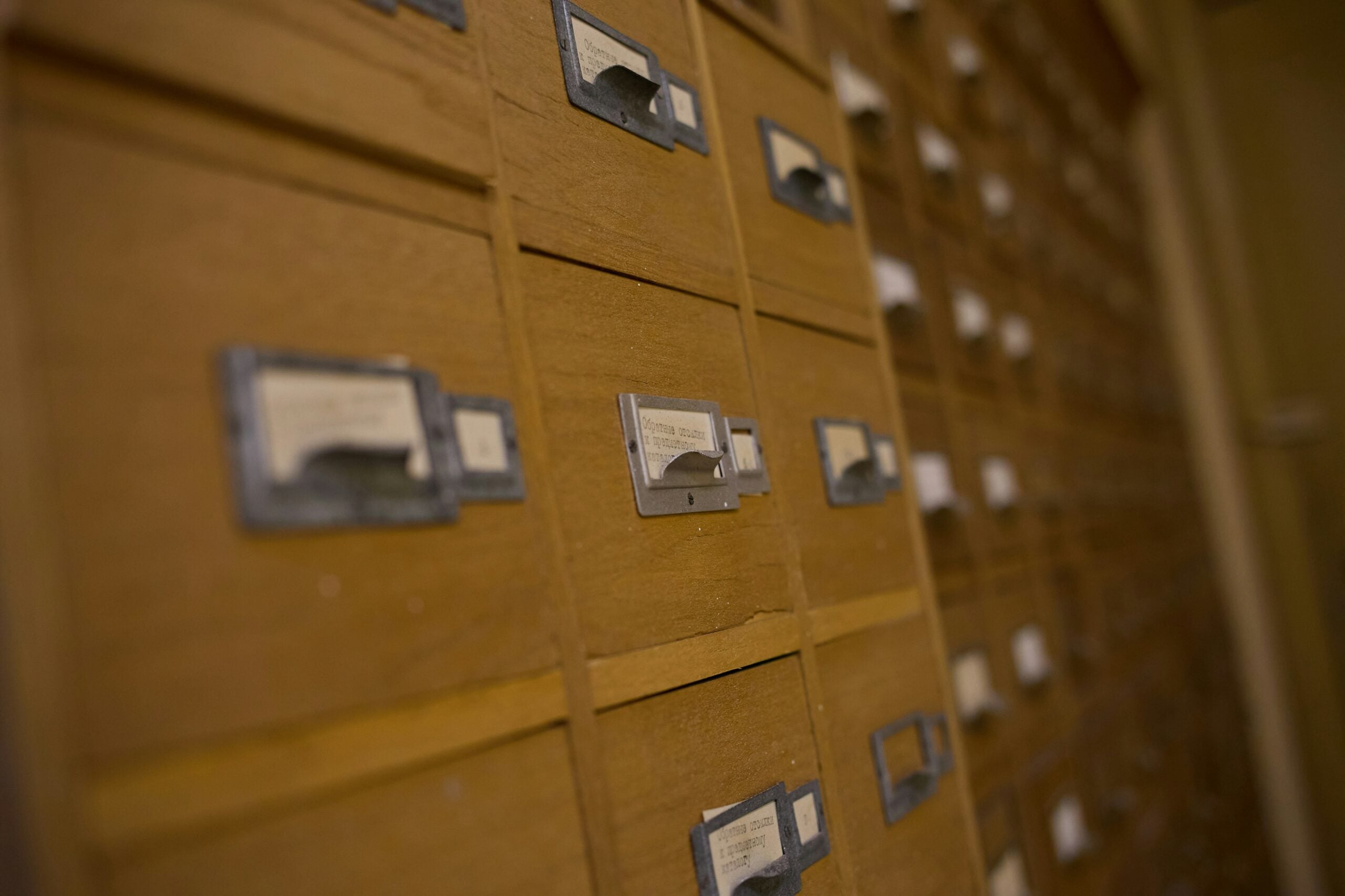 Close-up of wooden library card catalog drawers with metal label holders