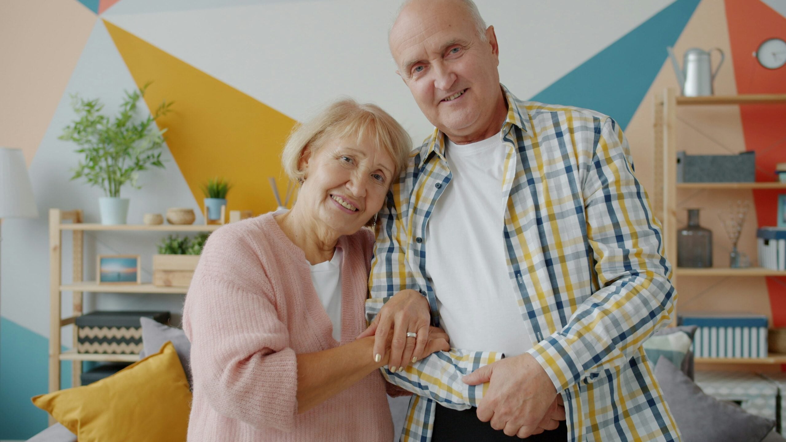 Elderly couple smiling together in a colorful room